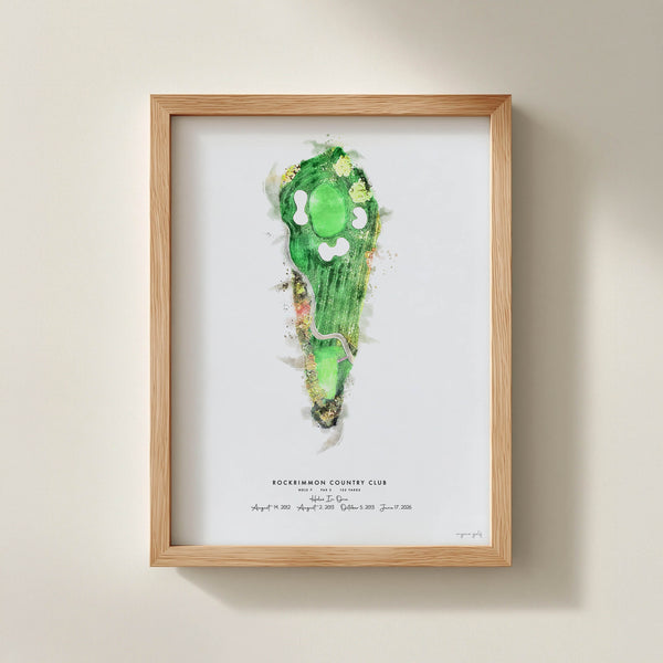 A framed custom golf art print featuring a green watercolor golf hole illustration on a white background, housed in a light natural red oak wood frame and mounted on a beige wall.