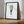 A framed golf art print featuring a watercolor-style footprint design with green and blue tones, leaning against a white wall on a light wood floor. The print includes the text 'PINE VALLEY' and small golf course references, with a black frame.