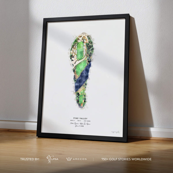 A framed golf art print featuring a watercolor-style footprint design with green and blue tones, leaning against a white wall on a light wood floor. The print includes the text 'PINE VALLEY' and small golf course references, with a black frame.